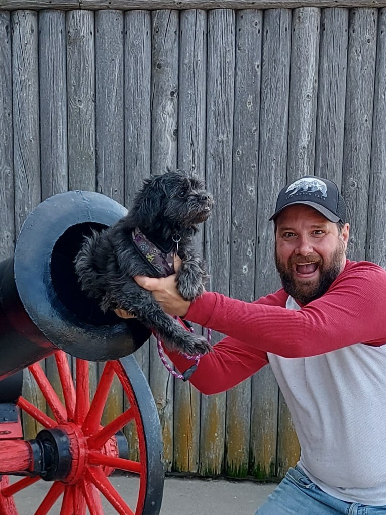 A man loading his dog into a cannon.